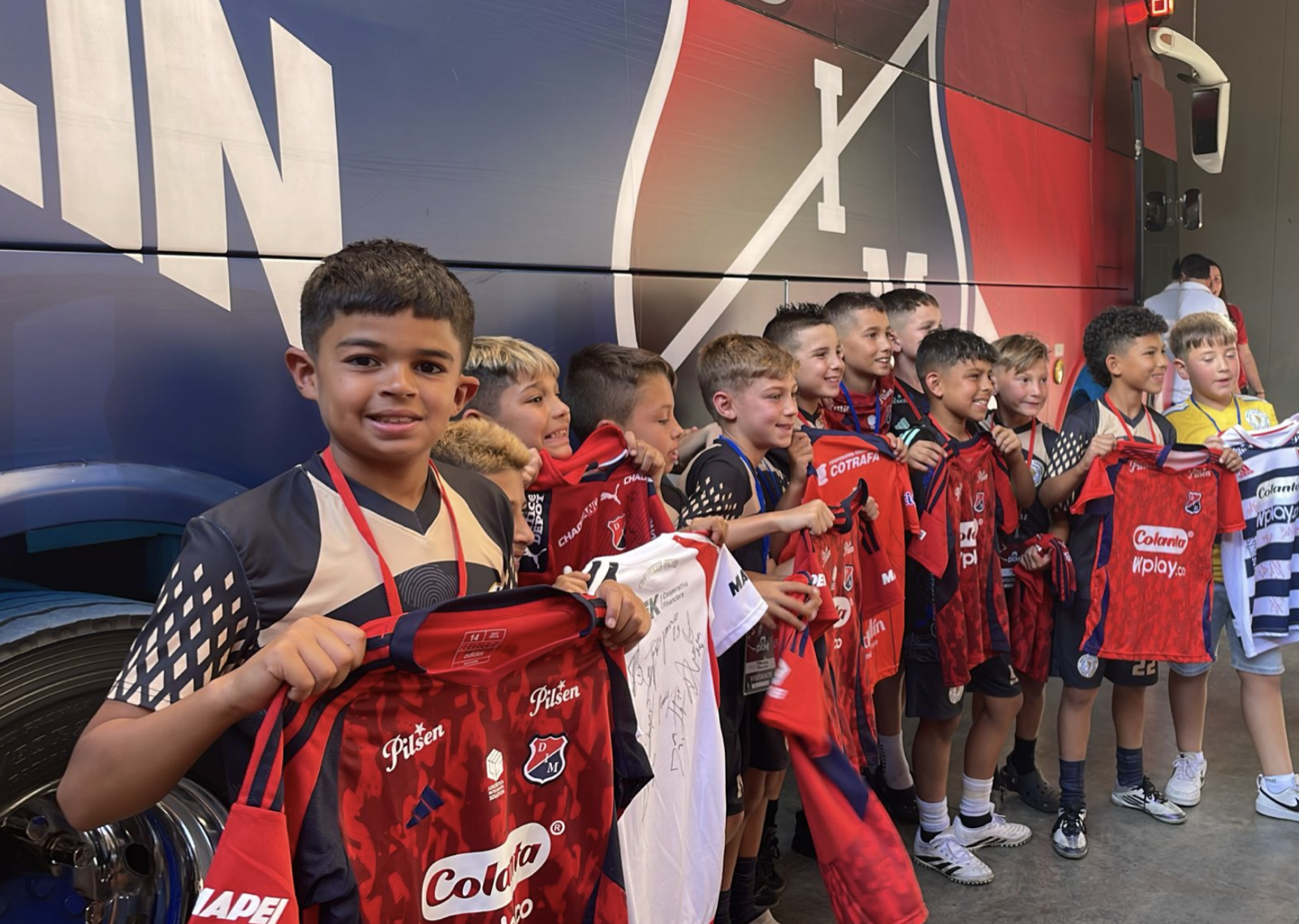 Jugadores jóvenes mostrando camisetas después de una experiencia de fútbol